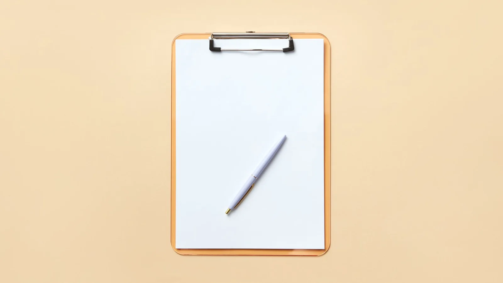 A clipboard holding a blank sheet of paper and a pen on a plain pale orange background